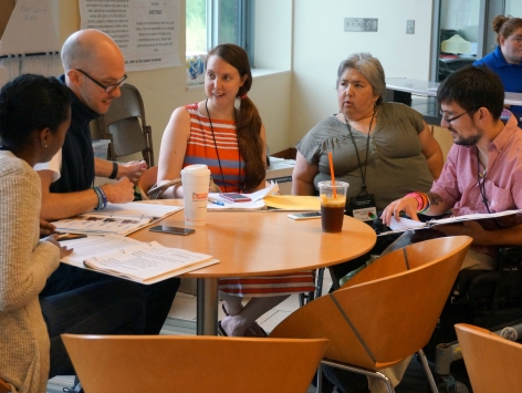 Group of women and male members sitting around a coffee table, discussing plans for an upcoming event