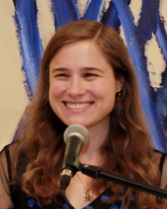 Allegra, a white woman with brown shoulder length hair, smiling for a picture