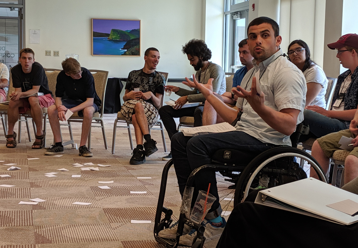 White man in a wheelchair leading a group exercise with a class