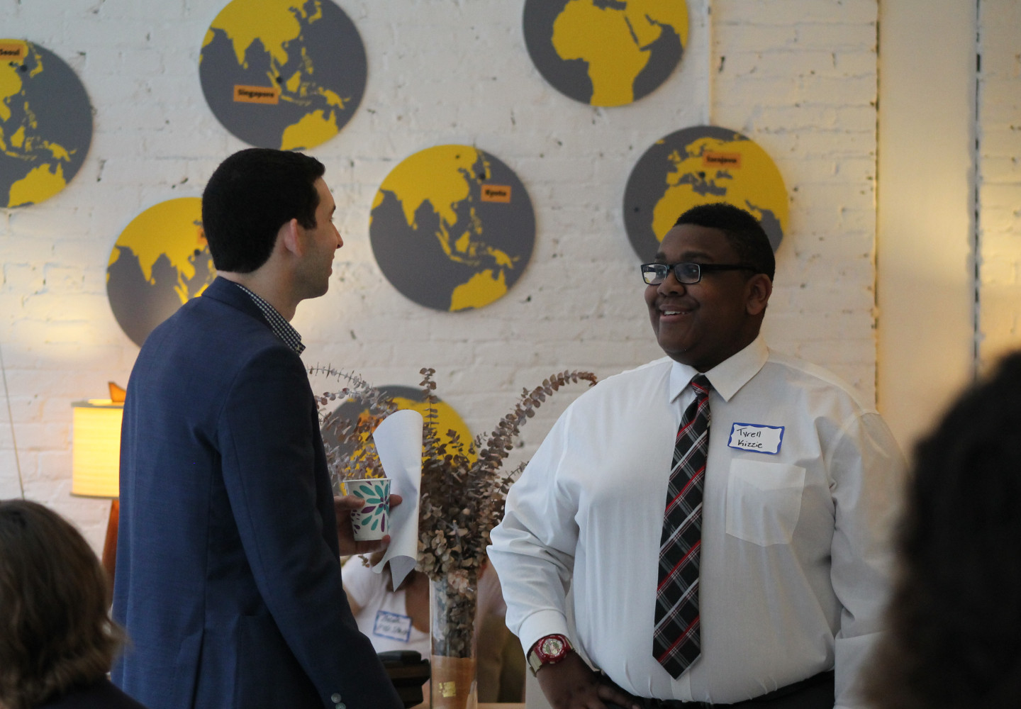 Young black man in a dress shirt and tie talks with a young white professional in a business coat